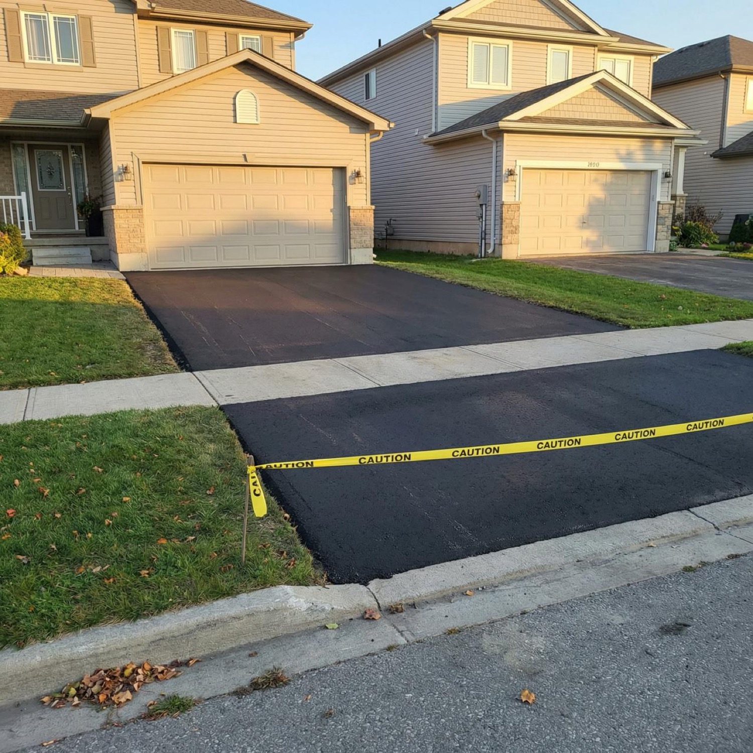 Two freshly paved residential driveways with caution tape in autumn