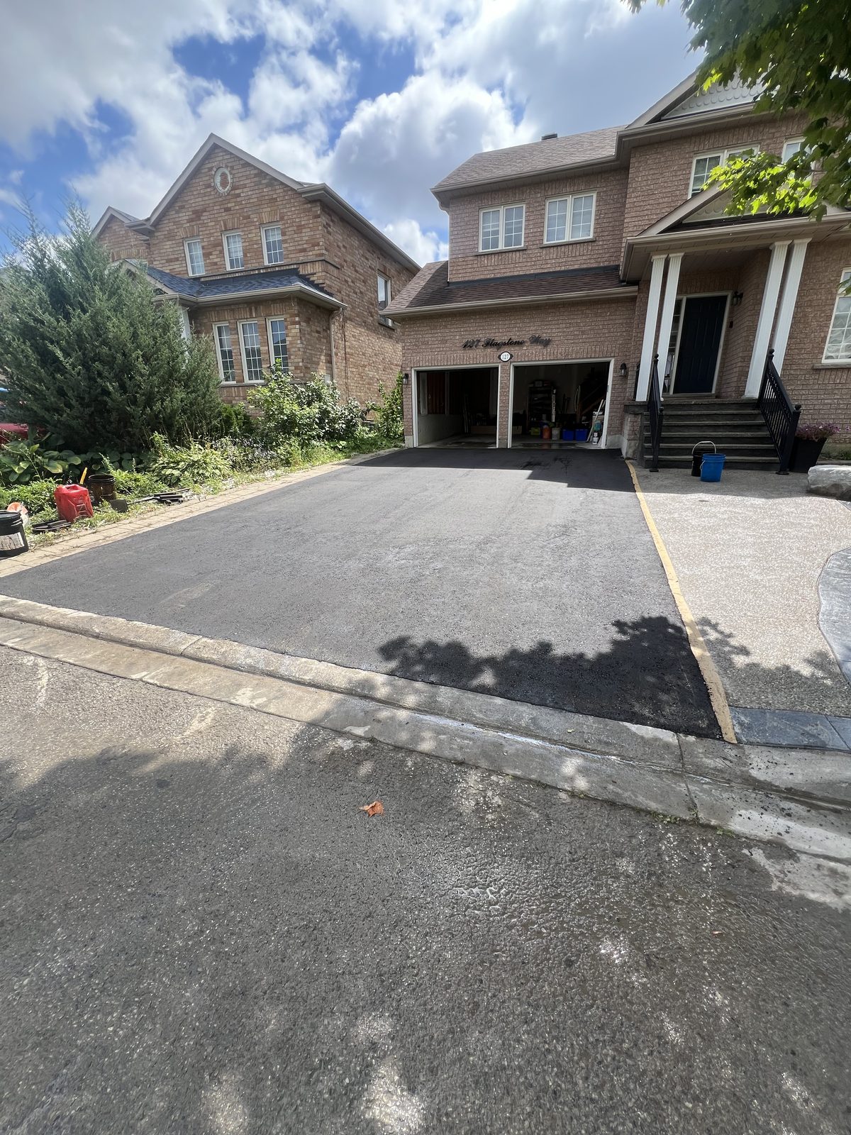 Newly paved smooth asphalt driveway with clean edges leading to a brick home garage in the GTA