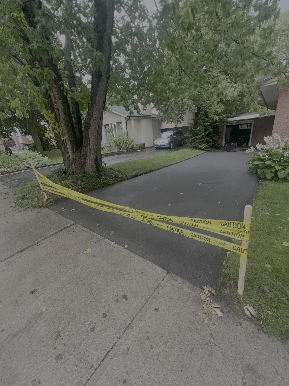 Newly paved smooth asphalt residential driveway with caution tape while curing in the Greater Toronto Area