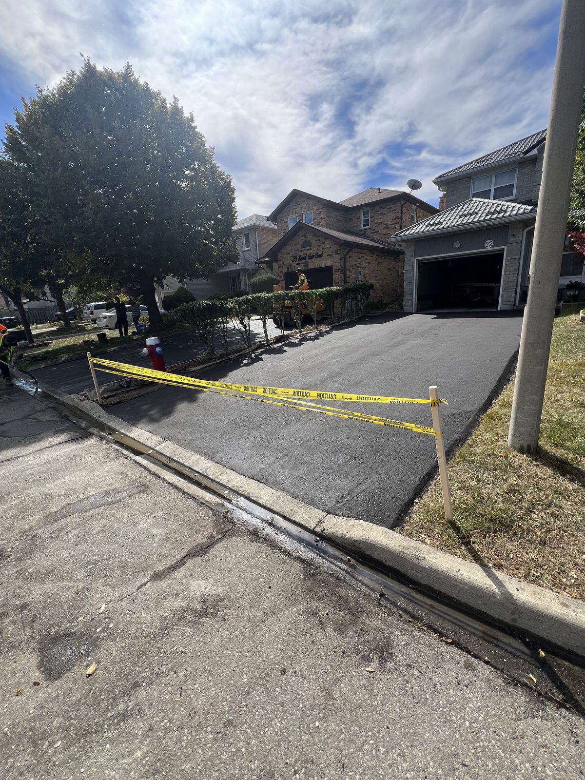 Newly paved asphalt driveway with caution tape at a GTA home, showing smooth fresh blacktop and clean sealed edges