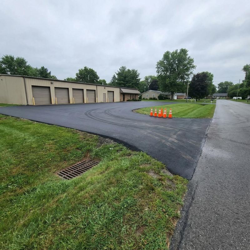 Freshly paved commercial parking lot beside an industrial building
