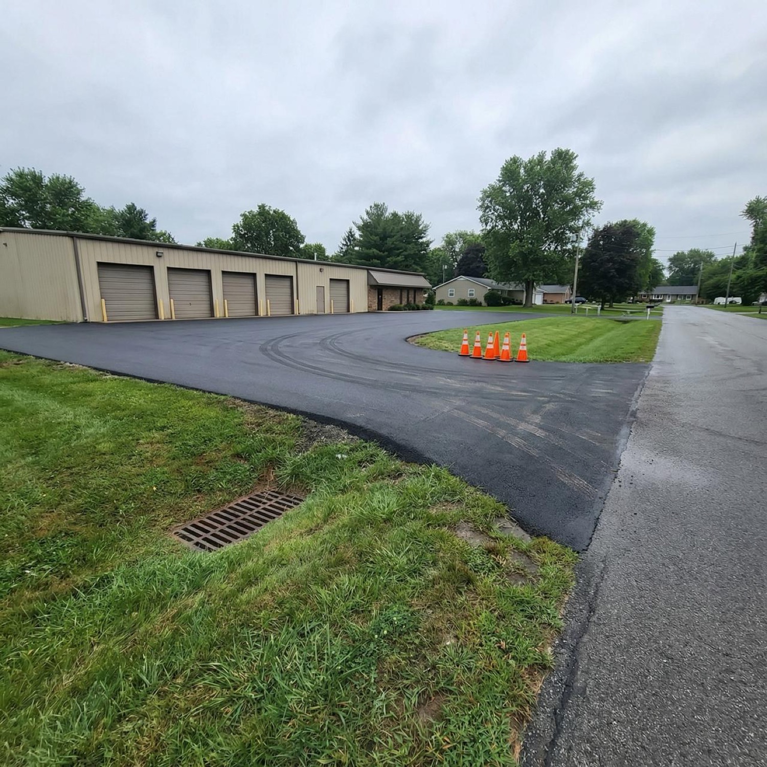 Freshly paved commercial parking lot beside an industrial building